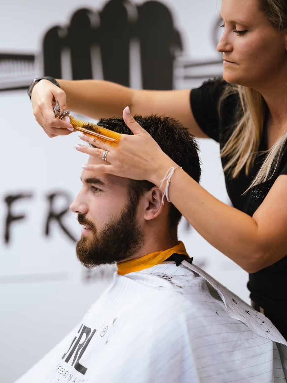 A man getting a haircut from a woman